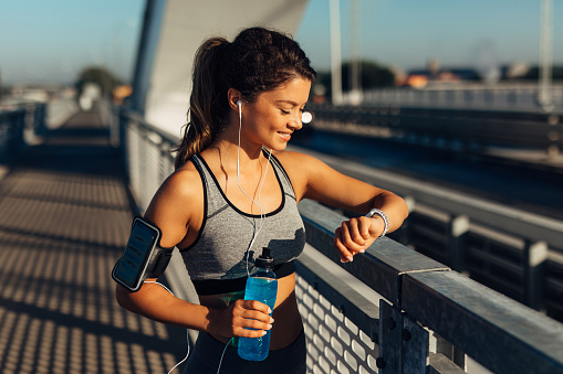 Female runner taking a break from running workout and reviewing info on her smart watch