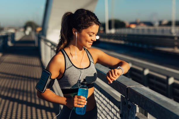 Female runner checking info on smart watch Female runner taking a break from running workout and reviewing info on her smart watch fitness tracker photos stock pictures, royalty-free photos & images