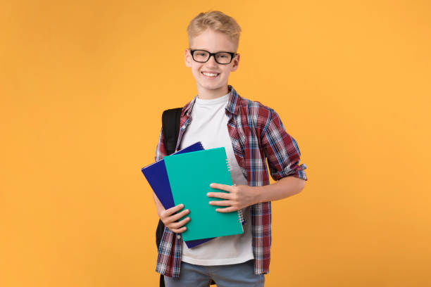 istock Smiling guy holding textbooks at orange studio background 1271736872