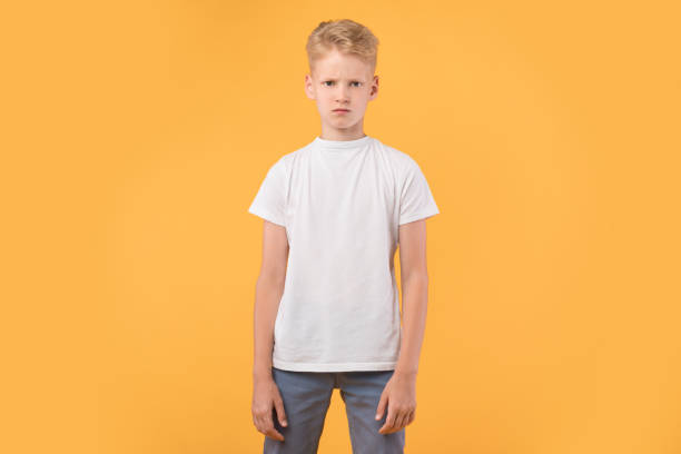 istock Portrait of sad angry boy standing at orange studio wall 1271738067