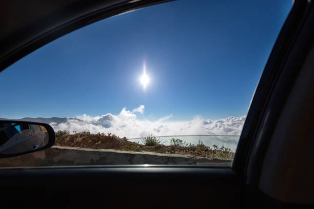 View from the car window to the mountains, blue sky and the sun. Car in the clouds. Traveling by vehicle. Active vacation.
