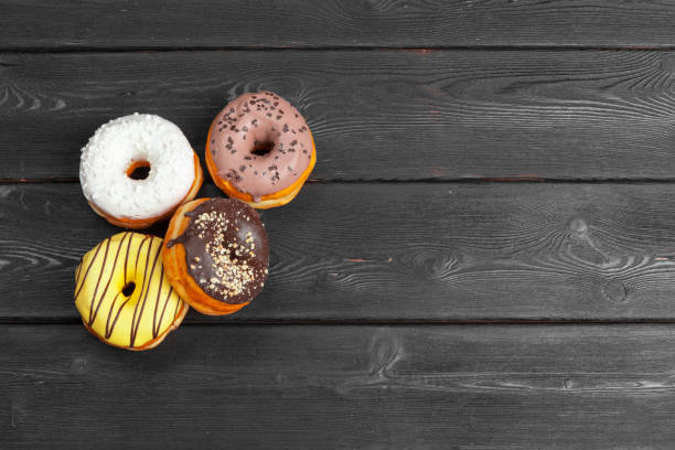 istock Colorful fresh donuts on dark black wooden surface 1271738714