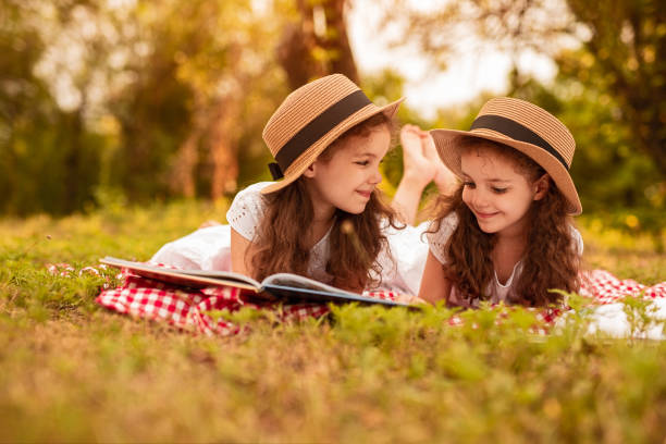 istock Happy twins reading book during picnic 1271739890