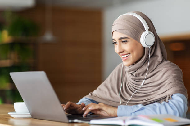 istock Cheerful muslim woman studying online, cafe interior 1271740076