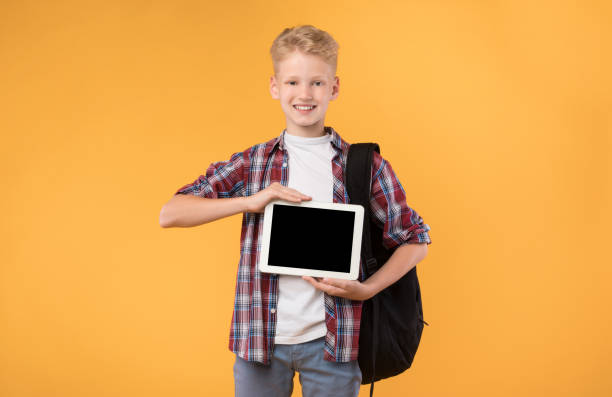 istock Smiling schoolboy showing tablet screen at camera 1271740234