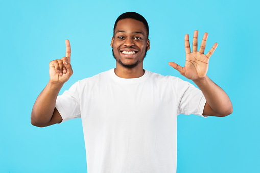African Guy Counting Showing Number Six Standing Over Blue Background photo