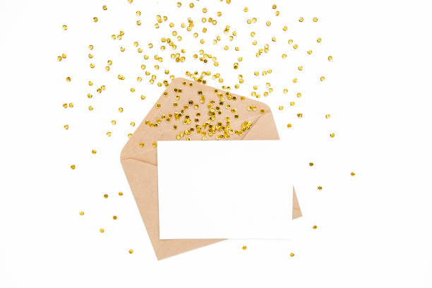 istock Styled desk with envelope, blank card and golden confetti isolated on a white background. Flat lay. Mockup template. View from above 1271740347