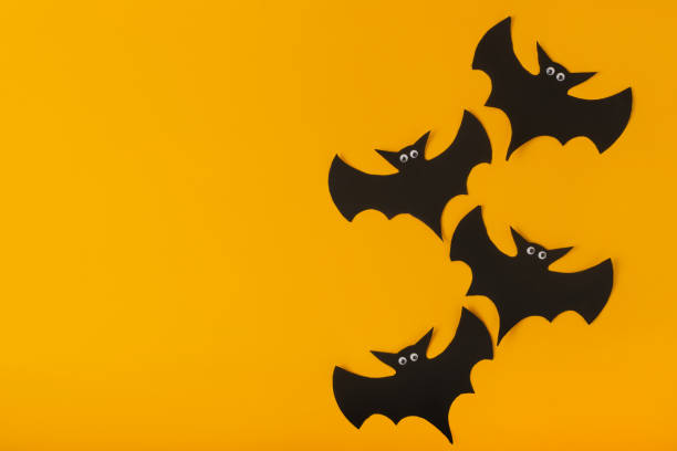 istock Black bats with eyes on a yellow background. Copy space. 1271741729