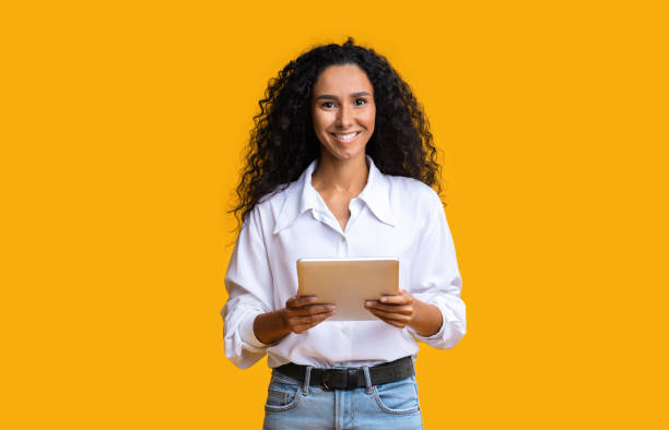 istock Curly Brunette Woman Posing With Digital Tablet In Hands Over Yellow Background 1271743073