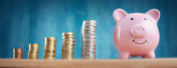 istock Piggy bank with stacked coins on blue background 1271748006