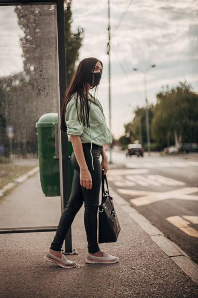 istock One woman with protective face mask waiting for a bus 1271749466