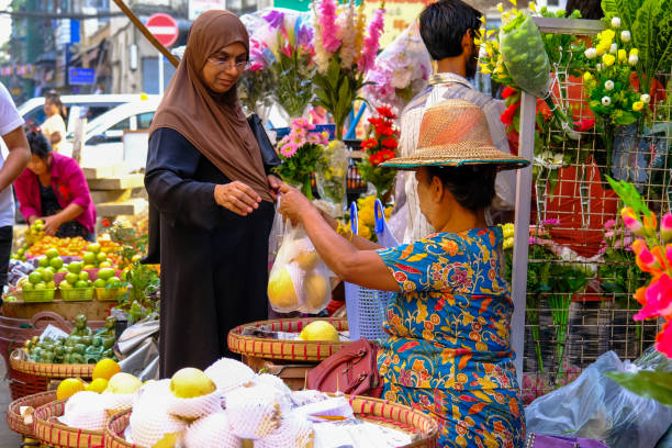 Colorful Yangon market. Muslim woman doing shopping, giving the money while completing the shopping.