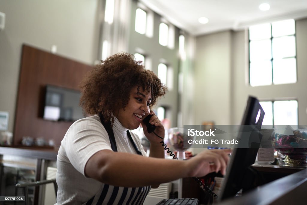 Waitress registering client's order in a computer at coffee shop Owner Stock Photo