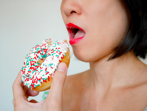 Woman eating doughnut with colorful sprinkles