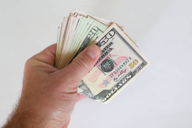 hand holds a wad of cash - money roll imagens e fotografias de stock