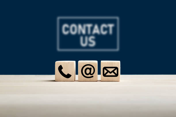 青の背景に私たちに連絡テキストと木製キューブ上の電話や電子メールのアイコン。web ページは、当社に連絡するか、電子メール マーケティングの概念を問い合わせてください。 - お問い合わせ ストックフォトと画像