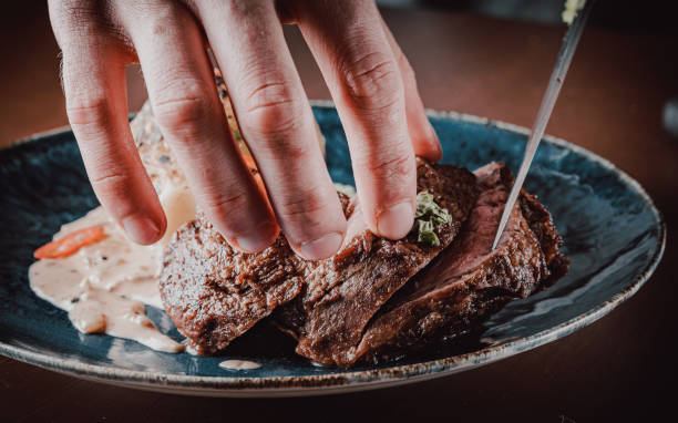 istock chef hand cut Grilled beef steak filet mignon in plate on wooden table 1271755650