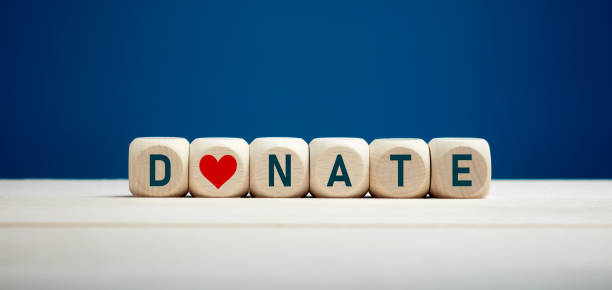 The word donate on wooden blocks with heart icon against blue background. Charity and donation. The word donate on wooden blocks with heart icon against blue background. Charity and donation concept. help single word stock pictures, royalty-free photos & images