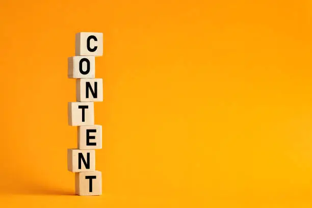 The word content on stacked wooden cubes with yellow background. Content creation or management in business information technologies.