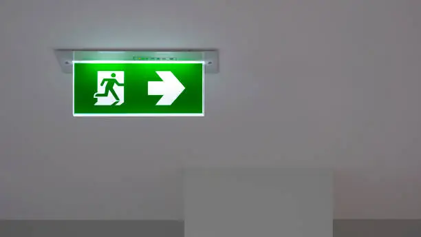Photo of Green emergency exit sign on ceiling inside of building