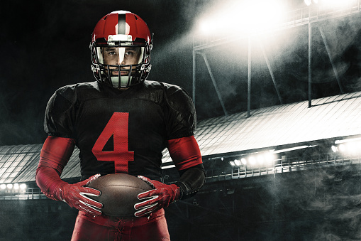 American Football player on stadium with smoke and lights.