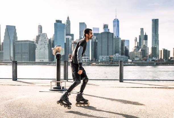 Side view of a skater by the East River in New York City, with the skyscrapers of the Manhattan cityscape in the distance.