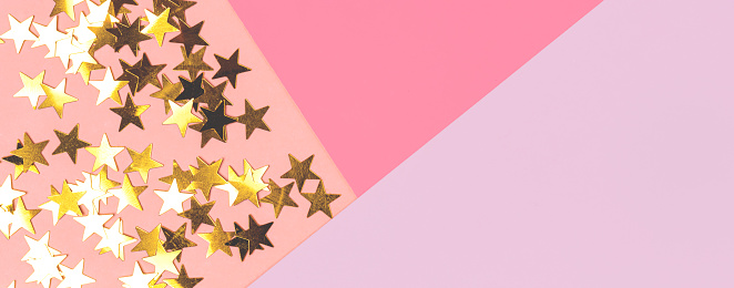 Festive background. Gold stars on a multicolored pastel background top view. Free space for text. Valentine's Day, Birthday or Mother's Day. Time to celebrate concept.