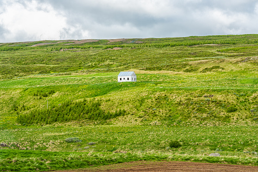 Landscape view of Iceland meadow green grass hill open field near Skutustadagigar and lake Myvatn during cloudy day and small house in summer