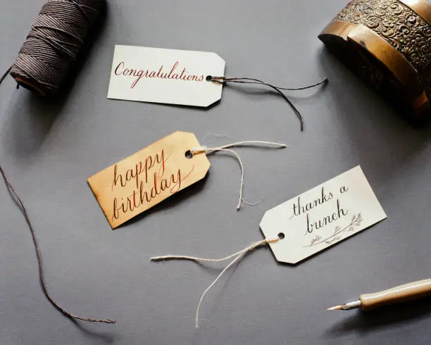 Photo of Gift parcel tags with brass inkwell and twine on slate gray background