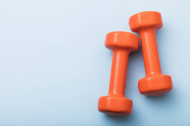 istock Orange dumbbells on a blue background with copy space, top view 1271767077