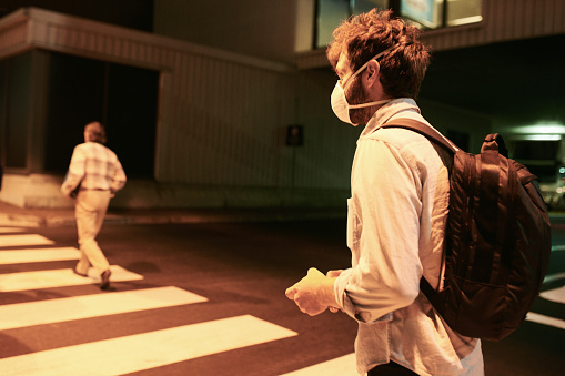 Shot of a young man wearing a mask and using a smartphone on the runway at an airport