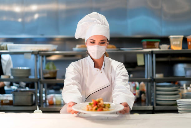 istock Chef working at a restaurant during the pandemic wearing a facemask while presenting a plate 1271768786