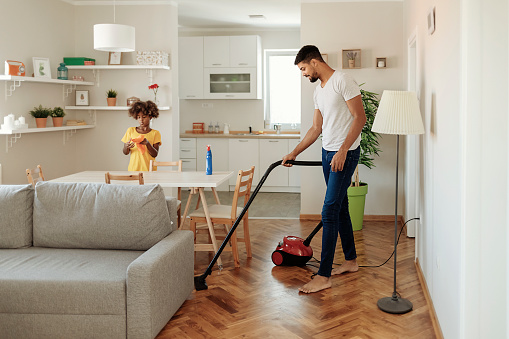 Happy Family Cleans the Room. Father and Daughter Do the Cleaning in the House. A Young Man and Child Girl Are Dusting
