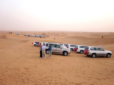 A large mixed group of tourist from a cruise ship docked in Bubai, UAE and the all-terrain vehicles gather in the desert west of the city for a sightseeing and cultural tour that will last into the night hours.  Image taken on April, 2012 and GPS coordinates are attached to the image if needed