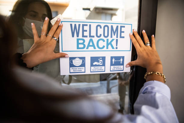 Woman applying "Welcome Back" sign to the school entrance Woman applying "Welcome Back" sign to the school entrance after covid-19 pandemic, every school is open to welcome the students again. reopening photos stock pictures, royalty-free photos & images