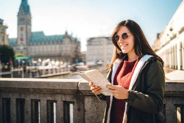 Young, woman, tourist, reading a map wearing a sunglasses. Jungfernstieg, Hamburg, Germany.