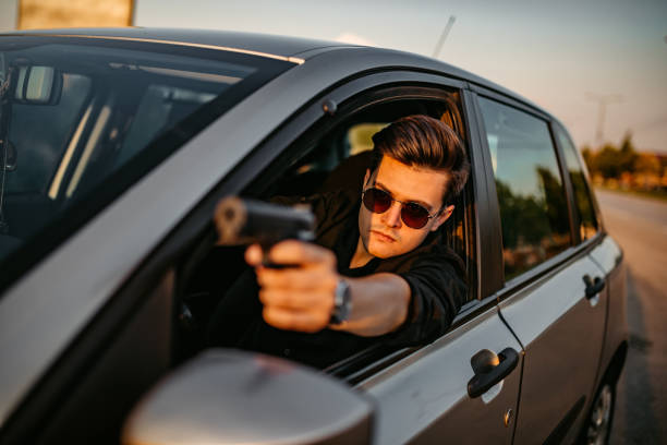 istock Detective in car aiming with gun through window 1271779340