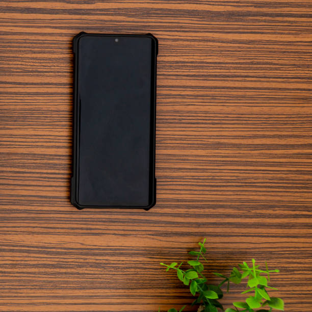istock A black mobile phone on a striped brown working table with a calculator and a green plant 1271780198