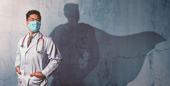 Médicos Valientes con su sombra de superhéroe en la pared. Concepto de hombre poderoso photo