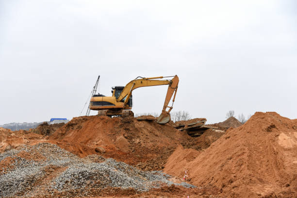 istock Excavator working at construction site. Backhoe during earthworks. Digging ground for the foundation and for laying sewer pipes district heating. Earth-moving heavy equipment 1271784055