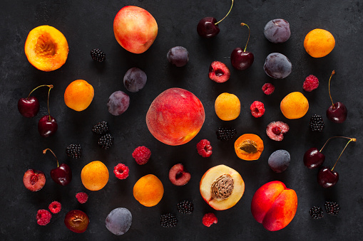 raspberries, currants, apricots, peaches, cherries and plums on a dark background
