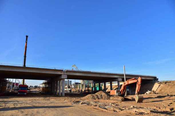istock Excavator working at construction highway ramps and bridgeworks. Roundabout and traffic bridge construction. Road work on traffic highway, road intersection junction and freeway. Bridge project works 1271785383