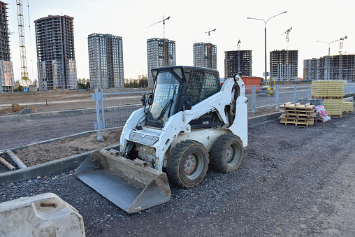 Bobcat skid-steer loader for loading and unloading works on city streets. ompact construction equipment for work in limited conditions. Road repair at construction site