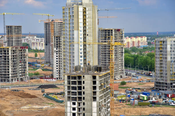 istock Aerial view on the large construction site with tower cranes and builders in action. Multi-storey residential building is being constructed use of crane. Pour of concrete in formwork 1271788740