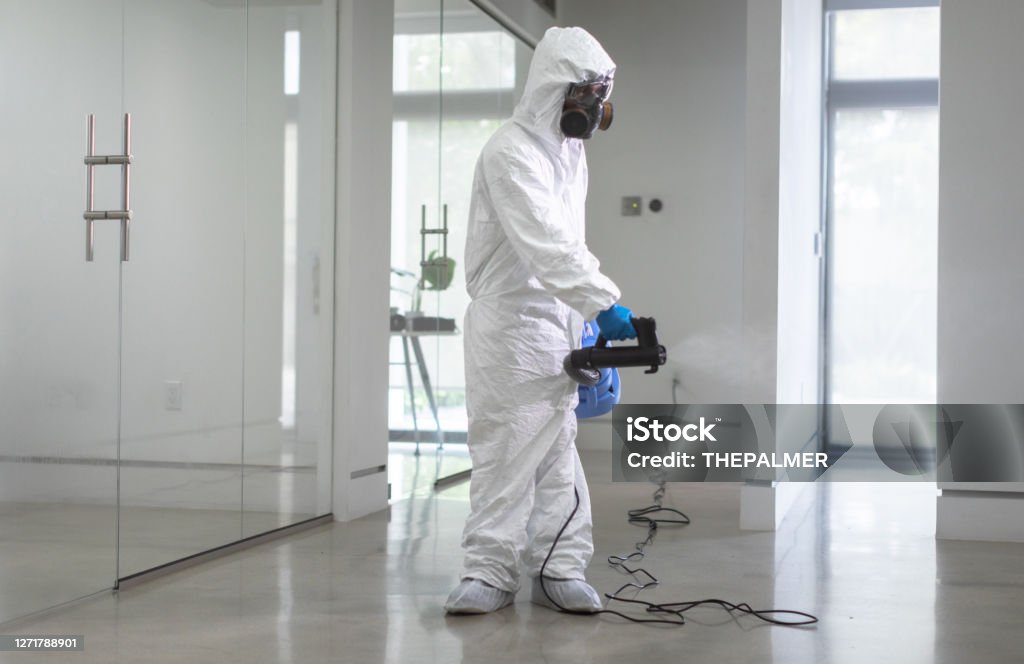 Office sanitation by professional worker coronavirus pandemic Disinfection Stock Photo