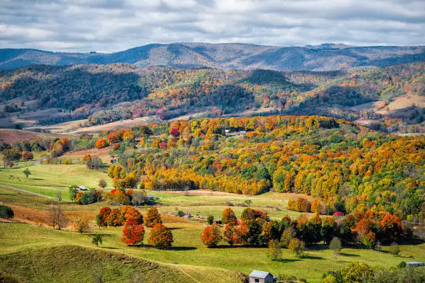 Photo of Autumn fall orange red colorful trees forest and farm houses buildings on rolling hills aerial above high angle view landscape in Monterey and Blue Grass, Highland County, Virginia