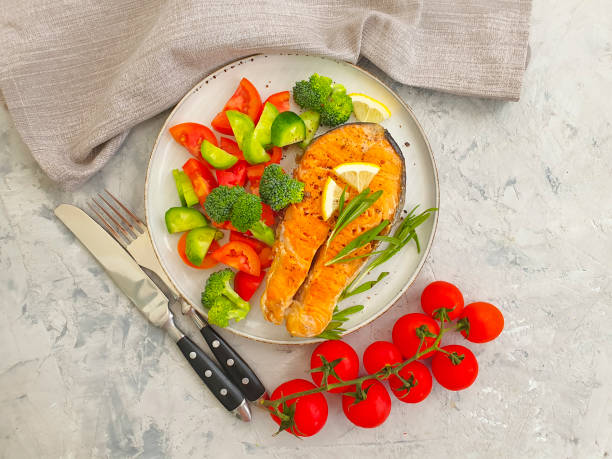 istock fried salmon slice on a plate, tomato on concrete background 1271791459