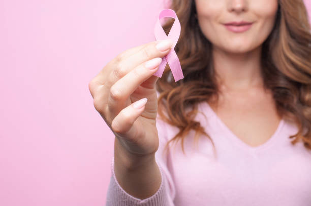 mujer en suéter rosa con cinta rosa que apoya la campaña de concienciación sobre el cáncer de mama - breast cancer fotografías e imágenes de stock