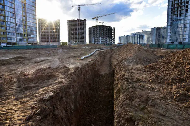 Photo of Trench for laying sewer pipes of the external sewage system at a construction site. Sanitary drainage system for a multi-story building. Civil infrastructure pipe, water lines and storm sewers