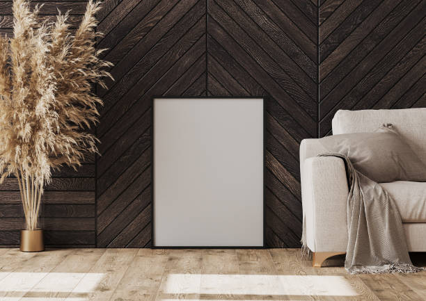 Empty frame mockup on the floor near sofa and dark wood wall, 3d rendering